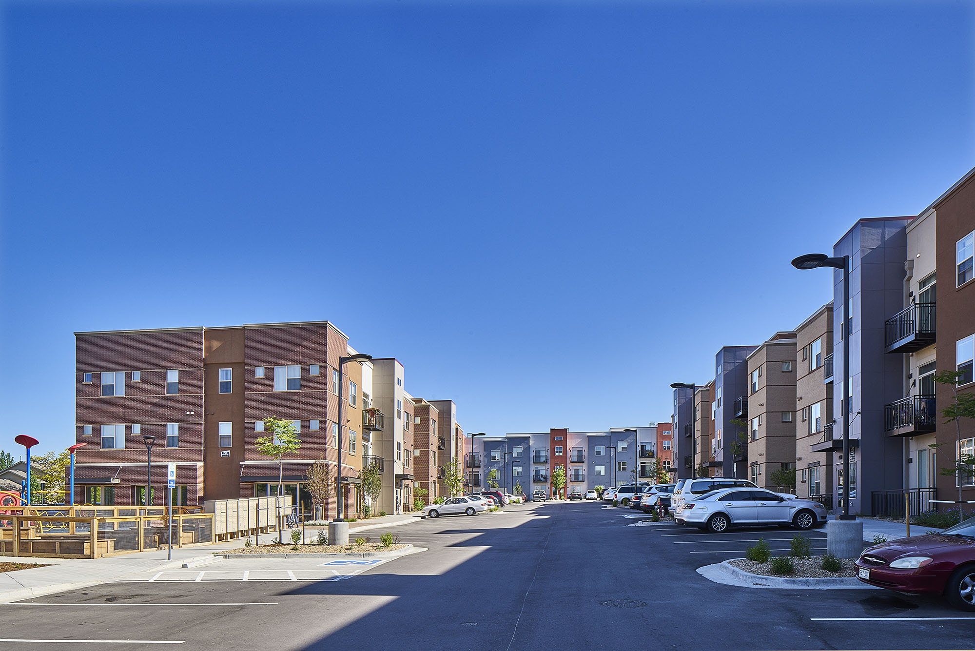 view of crissman apartment buildings from parking lot with playground in foreground