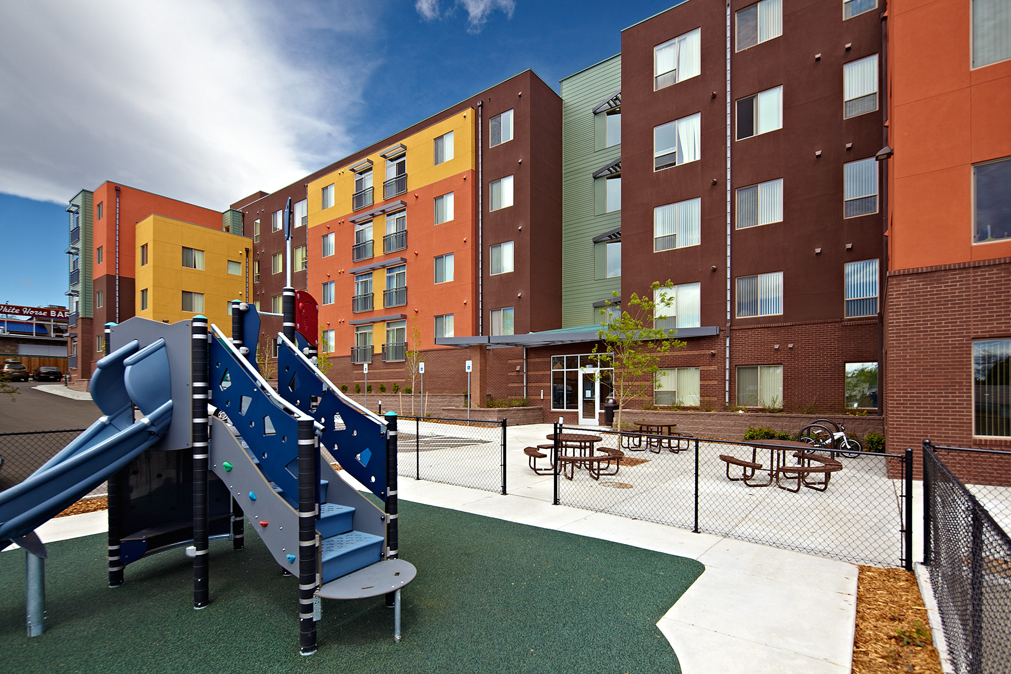 5 storey apartment building with windows overlooking playground and picnic seating